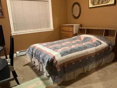 a bedroom with a bed and a dresser and a window at Barry and Elaine in Abbotsford