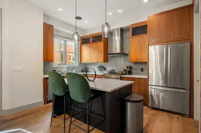 a kitchen with wooden cabinets and a stainless steel refrigerator at THE Getaway For BIG Groups-DT in Calgary