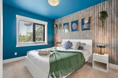 a blue bedroom with a bed and a window at *Everything*| Hot Tub| Sauna| Pool table|Game Room in Calgary