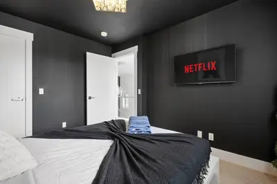 a black bedroom with a bed and a tv on the wall at *Everything*| Hot Tub| Sauna| Pool table|Game Room in Calgary