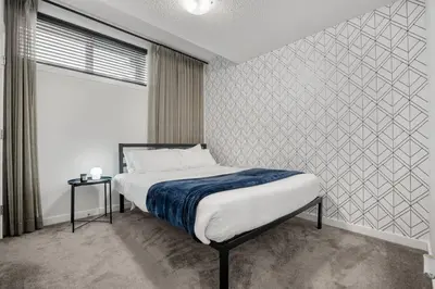 a bedroom with a bed and a large window at Modern Suburban Retreat in Ambleton Stylish Comfort Near Parks and Trails in Calgary
