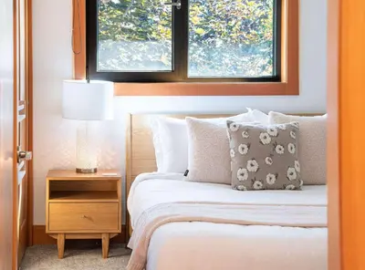 a bedroom with a bed with a nightstand and two windows at Cartier Chalet in Revelstoke