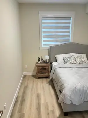 a bedroom with a bed and a window and a wooden floor at Prince George Cozy Suite in Prince George
