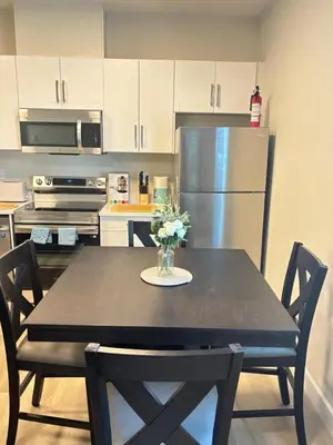 a kitchen with a table with chairs and a refrigerator at Prince George Cozy Suite in Prince George
