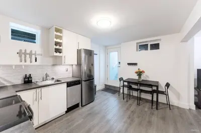 a kitchen with a table and a stainless steel refrigerator at Lynn Valley 2BR Suite By Grouse Mtn & Lynn Canyon in North Vancouver