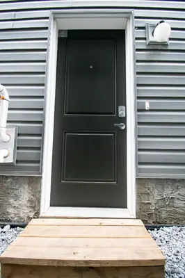a black door on a house with a wooden doorstep at Cozy Luxe Suites in Calgary
