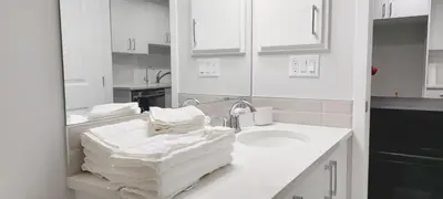 a white bathroom with a sink and a mirror at Cozy Luxe Suites in Calgary
