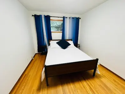 a small bedroom with a bed with blue curtains at mysev property in Calgary