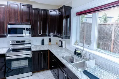 a kitchen with dark wooden cabinets and a sink at Northern Solace, 2 beds, 2 baths, 5 min to airport in Yellowknife
