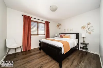 a bedroom with a bed and a chair and a window at 6BDRM Chic Modern Home-Fireplace-BBQ-Sleeps 18! in Edmonton