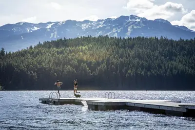 two people standing on a dock in the water at 2BR in Symphony, Hot Tub, Gas Fireplace, Epic Village Location, Ski Shuttle in Whistler