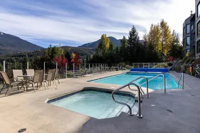 a swimming pool with chairs and a table and a table at 2BR in Ironwood, Stunning Mountain Views, Shared Hot Tub and Pool, Fireplace, Parking in Whistler