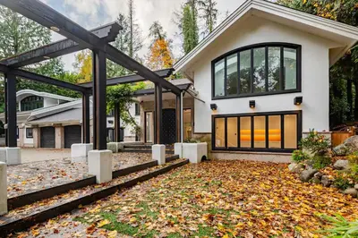 a house with autumn leaves in front of it at Serene 5-Bedroom Nature Retreat in West Vancouver