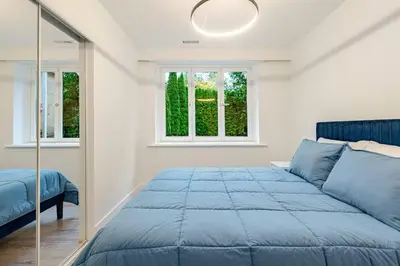 a bedroom with a blue bed and two windows at Serene 5-Bedroom Nature Retreat in West Vancouver