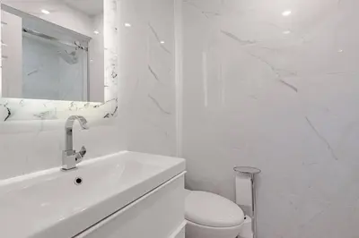 a white bathroom with a toilet and a sink at Serene 5-Bedroom Nature Retreat in West Vancouver
