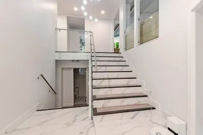 a staircase in a house with white walls and marble floors at Serene 5-Bedroom Nature Retreat in West Vancouver