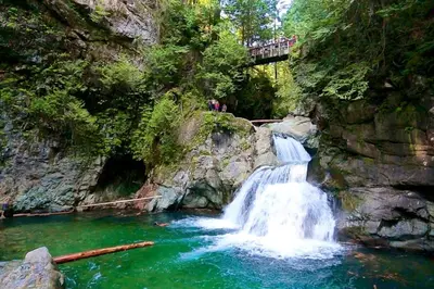 a waterfall in a river with a bridge over it at Spacious 1BR Suite Near Capilano Bridge & Trails in North Vancouver