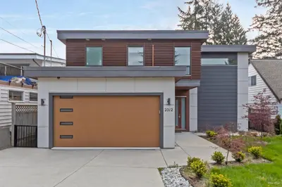 a house with a brown garage door at Spacious 1BR Suite Near Capilano Bridge & Trails in North Vancouver