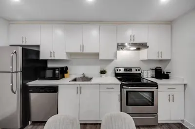 a kitchen with white cabinets and stainless steel appliances at Modern 2Bed Suite Near Capilano Bridge & Trails in North Vancouver