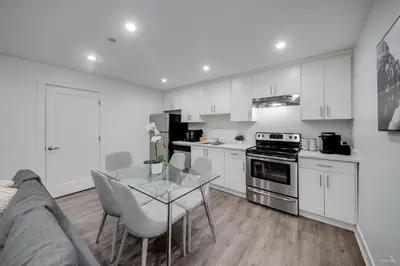a kitchen with white cabinets and a glass table at Modern 2Bed Suite Near Capilano Bridge & Trails in North Vancouver
