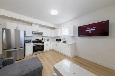 a kitchen with white cabinets and a flat screen tv at Spacious 6BR Home with Terrace Views and Parking nearby parks golf and resorts in Chilliwack