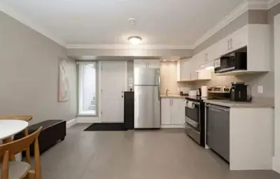 a kitchen with a refrigerator and a table in it at Stylish Home in Van West Side Near YVR&DT in Vancouver