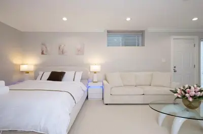 a white bedroom with a large bed and a couch at Stylish Home in Van West Side Near YVR&DT in Vancouver