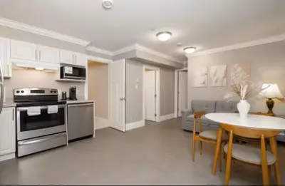 a kitchen and dining room with a table and a stove at Stylish Home in Van West Side Near YVR&DT in Vancouver