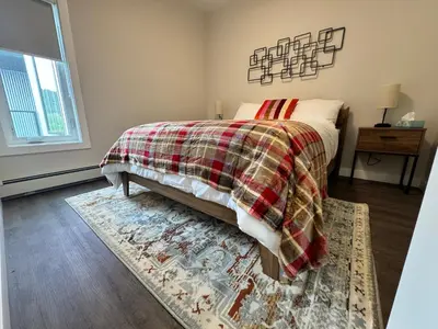 a bedroom with a bed with a blanket and a rug at Paradise Point - Hot Tub & Mountain Views in Golden