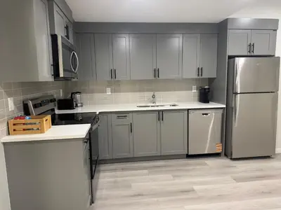 a kitchen with gray cabinets and a stainless steel refrigerator at Rockies Golden Retreat 2BR Suite at Glacier Ridge NW Calgary in Calgary