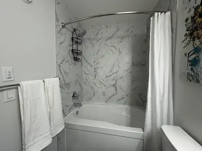a bathroom with a white tub and a marble wall at Family Friendly Rockies Retreat at Glacier Ridge NW Calgary in Calgary