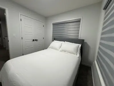 a bedroom with a white bed with two pillows at Family Friendly Rockies Retreat at Glacier Ridge NW Calgary in Calgary