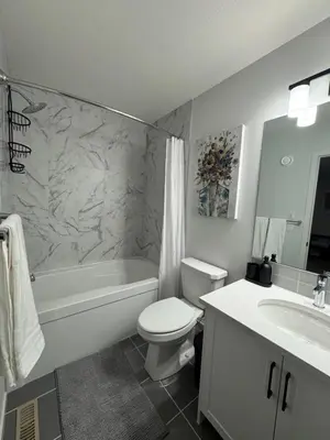 a bathroom with a toilet and a tub and a sink at Family Friendly Rockies Retreat at Glacier Ridge NW Calgary in Calgary