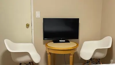 a tv sitting on a table with two white chairs at Cozy Ground-Floor Room with Private Bath and Separate Entry in Delta
