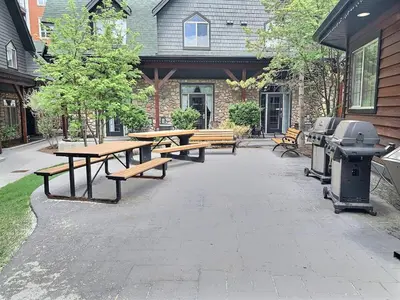 a patio with picnic tables and a grill at Marvellous Poolside Chalet - Pool & Hot Tub - Pets in Canmore