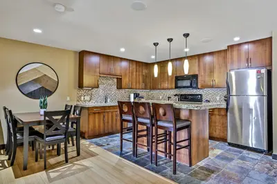 a kitchen with wooden cabinets and a stainless steel refrigerator at Fantastic Mountain View - Hot Tubs & Steam Room in Canmore