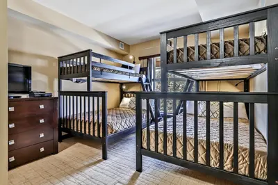 two bunk beds in a room with a tv at Fantastic Mountain View - Hot Tubs & Steam Room in Canmore