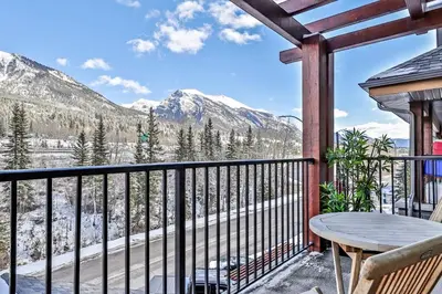 a balcony with a table and a view of mountains at Fantastic Mountain View - Hot Tubs & Steam Room in Canmore