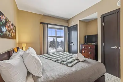 a bedroom with a large bed with a window at Stunning Condo - Hot Tubs & Steam Room - Pets Ok in Canmore