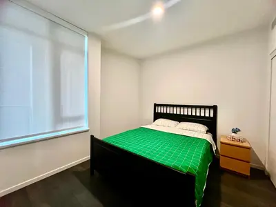 a bedroom with a bed with green sheets and a window at Warm and Cozy 1B1B near Richmond center in Richmond