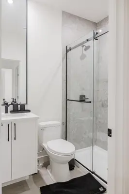 a white bathroom with a toilet and a shower at Brown Family Vacation Home in Leduc