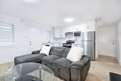 a living room with a couch and a kitchen at Bright & Modern Surrey Basement Suite with Queen Beds & Parking in Surrey