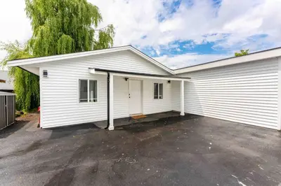 a white house with a garage at Lovely Coach House in Langley with Queen Beds Pkg in Langley