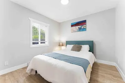 a white bedroom with a bed and a window at Lovely Coach House in Langley with Queen Beds Pkg in Langley