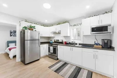 a kitchen with white cabinets and a stainless steel refrigerator at Lovely Coach House in Langley with Queen Beds Pkg in Langley