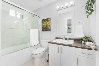 a white bathroom with a toilet and a glass shower at Lovely Coach House in Langley with Queen Beds Pkg in Langley