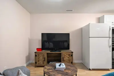 a living room with a tv and a white refrigerator at The Arizona 2BR Pet-Friendly Suite Calgary SE in Calgary