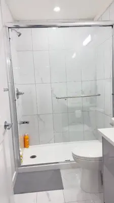 a white bathroom with a shower and a toilet at Zillion’s Bliss - Basement Suite in Calgary