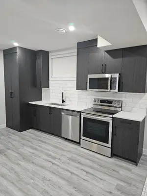 a kitchen with stainless steel appliances and wooden cabinets at Cozy on 516 in Airdrie