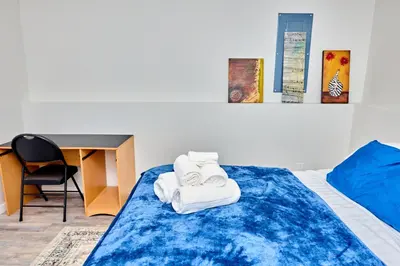 a bedroom with a bed with a desk and towels at Anukc in Prince George